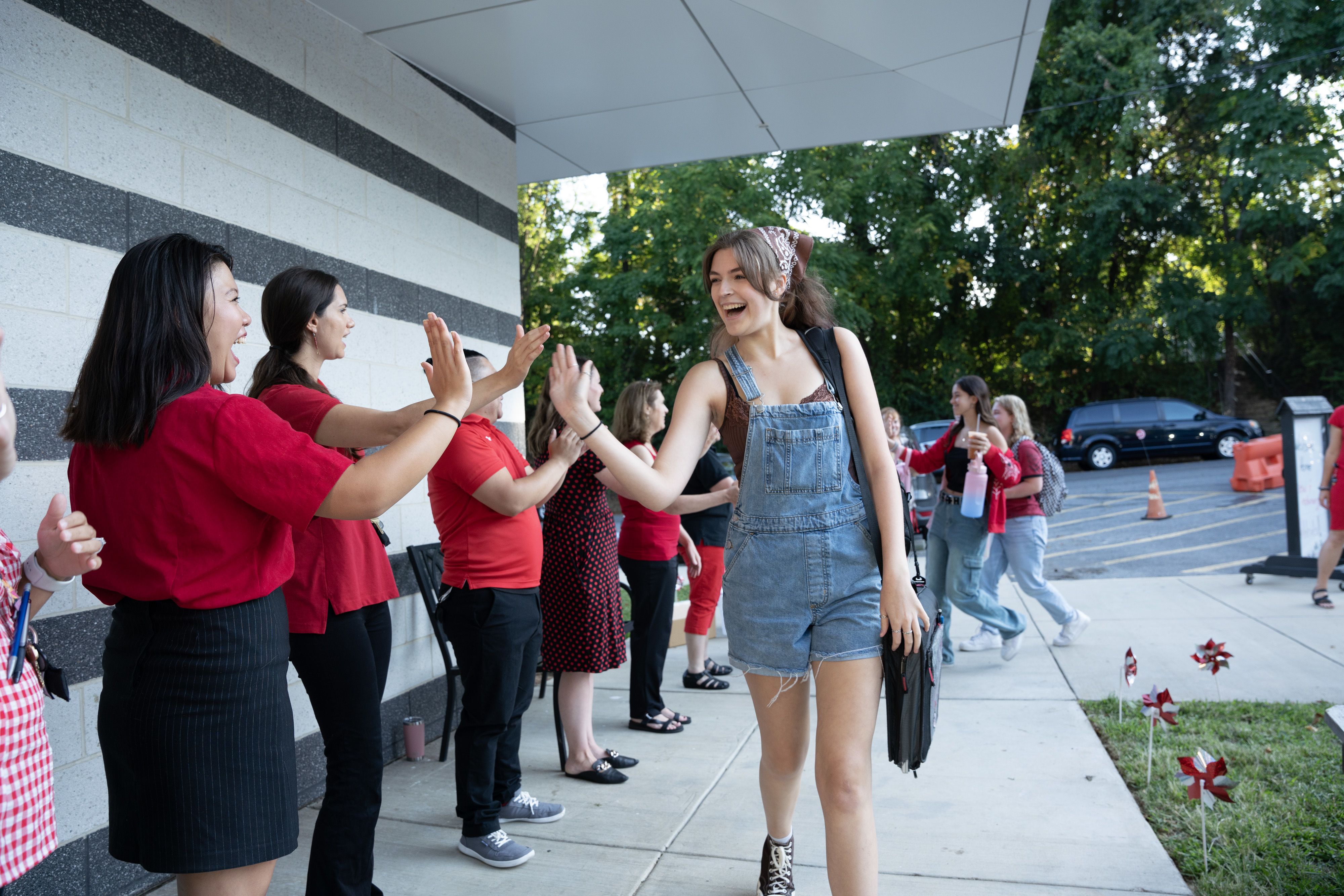 High school student high-fives teachers on the first day of school.